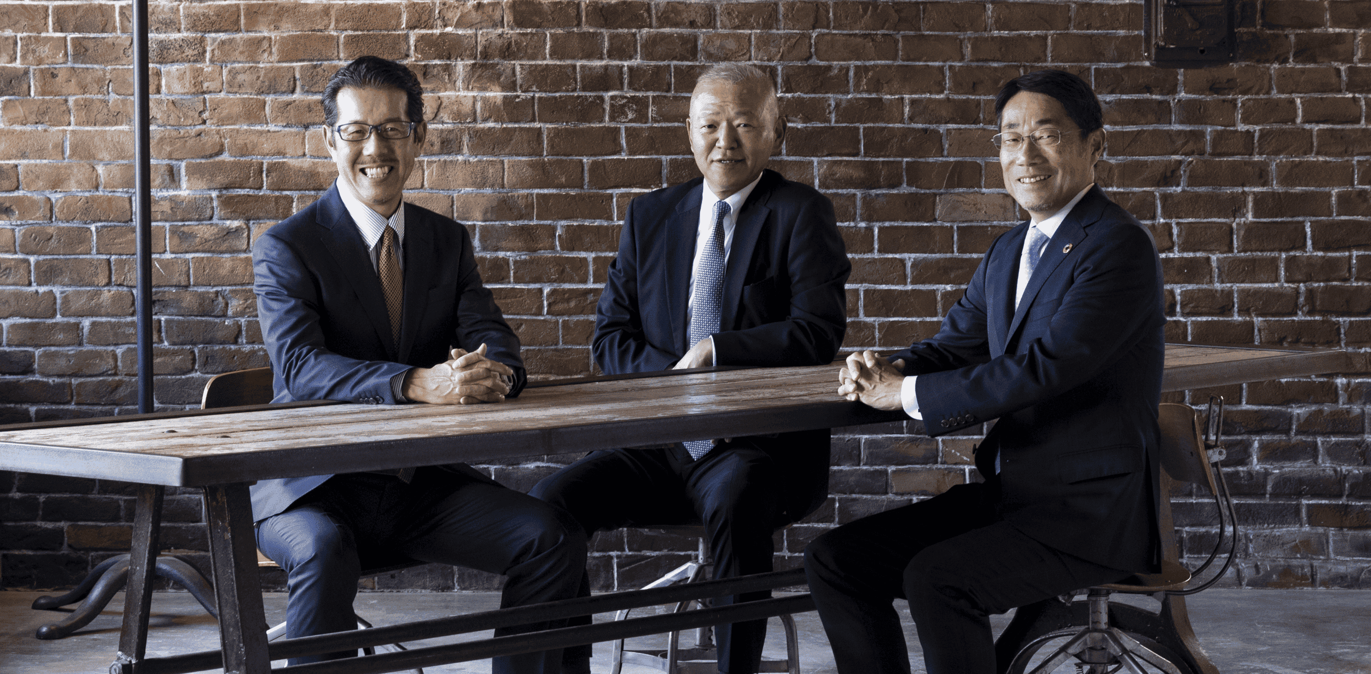 Three speakers are smiling warmly and chatting pleasantly.